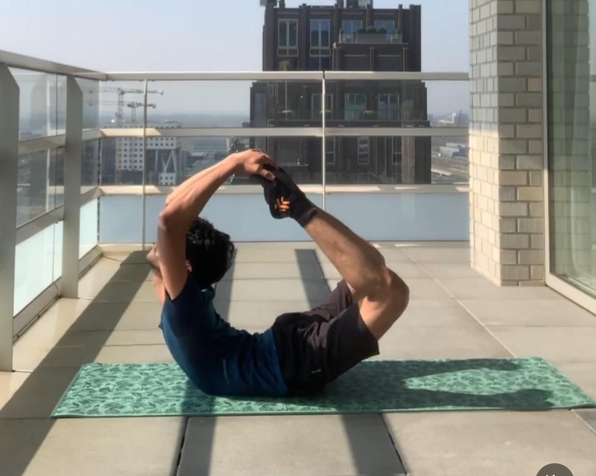 Farooq demonstrating bow pose above the Amsterdam skyline